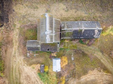 Eski bir kırmızı tahıl asansörü tarlada duruyor. Bina terk edilmiş ve bakımsız görünüyor.