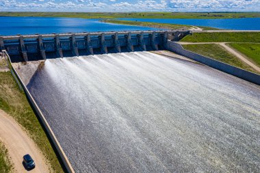 A large body of water with a dam and a car driving by. The water is white and the dam is gray clipart