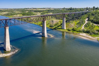 Bir köprü, aşağıdaki su manzaralı bir nehri kapsar. Köprü eski ve paslı, ama hala sağlam. Gökyüzü berrak ve mavi, ve su sakin. Huzurlu ve huzurlu bir sahne.