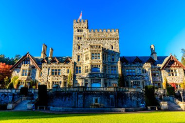 Üzerinde kırmızı bayrak dalgalanan büyük bir kale. Kale yemyeşil bir çimenlikle çevrili ve güzel bir gökyüzü manzarası var.