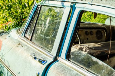 İçi mavi ve kirli ön camı olan bir araba. Araba eski ve çok paslı.