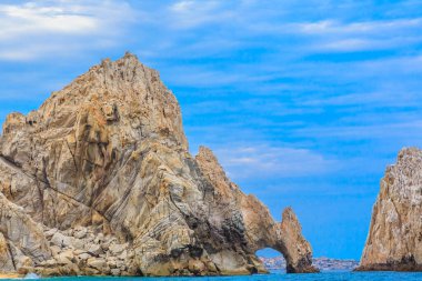 Ortasında büyük bir kemer olan kayalık bir uçurum. Kemer yolu büyük bir su kütlesiyle çevrilidir.