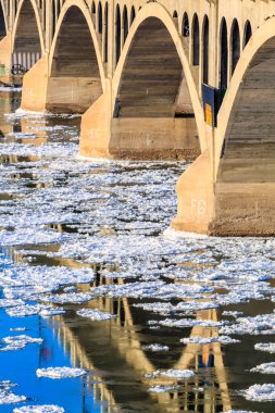 Üzerinde bir sürü buz olan bir köprü. Buz köprüyü ve altındaki suyu kaplıyor.