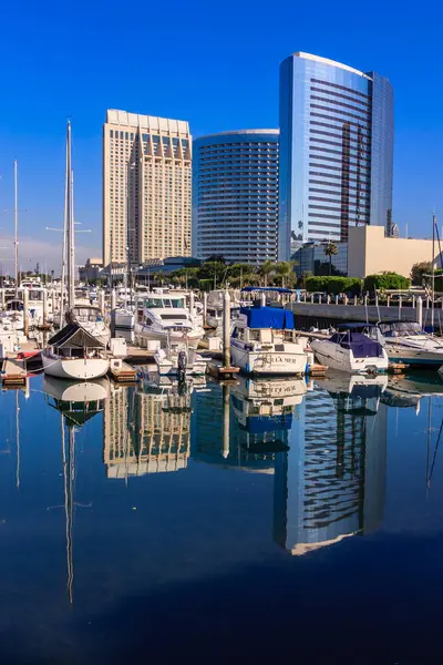 Suya büyük bir bina yansıtılır. Su sakin ve tekneler rıhtımda.