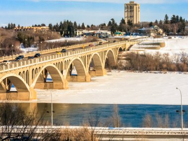 Bir köprü karlı bir kıyısı olan bir nehri kapsar. Köprü beyaz korkuluklu büyük bir kemer köprüdür. Köprü ağaçlar ve binalarla çevrili.