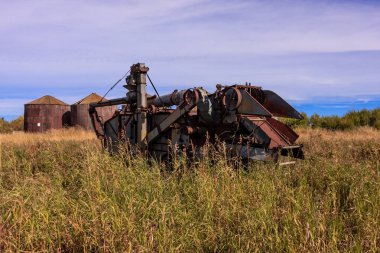 Eski, paslı bir biçerdöver uzun otların arasında oturur. Nostalji kavramı ve zaman geçişi