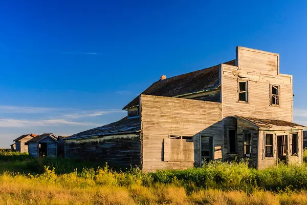 Büyük, bir sürü penceresi olan eski bir ev bir tarlada oturur. Gökyüzü mavi ve güneş ışıl ışıl parlıyor