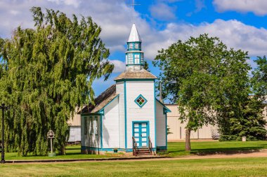 Mavi çatılı küçük beyaz bir kilise çimenli bir tarlada oturur. Kilise ağaçlarla çevrili ve o huzurlu ve huzurlu bir yer.