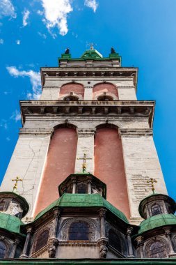 Yeşil çatılı ve tepesinde haç olan yüksek bir bina. Bina mavi bir gökyüzü ile çevrilidir.