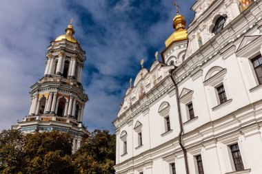 Altın kubbesi ve saat kulesi olan büyük beyaz bir bina. Bina ağaçlarla çevrili ve sakin bir atmosferi var.