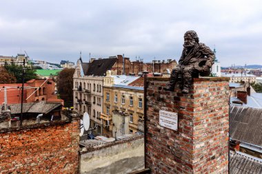 A statue of a man sits on a brick chimney in a city. The statue is surrounded by buildings and a brick chimney. The scene is quiet and peaceful, with the statue seeming to be in a contemplative mood clipart