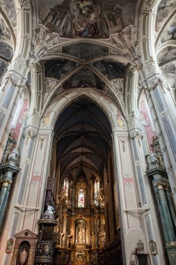 Bir sürü kemeri ve penceresi olan bir kilisenin içinde. Kemerler çok uzun ve pencereler çok büyük. Kilise çok eski ve çok fazla tarihi var.