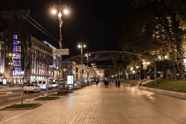 Geceleri insanların yürüdüğü ve arabaların sürdüğü bir şehir caddesi. Sokak ışıklarla aydınlandı ve atmosfer canlandı.
