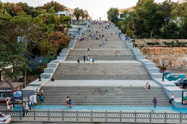 Bir grup insan çok dik bir merdivenden yukarı çıkıyorlar. Sahne çok kalabalık.