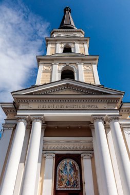 Arka planda mavi gökyüzü olan uzun beyaz bir kilise. Bina çok eski ve çok fazla detayı var.
