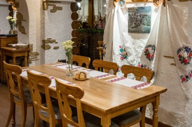 Üzerinde beyaz bir bez ve bir vazo çiçek olan ahşap bir yemek masası.