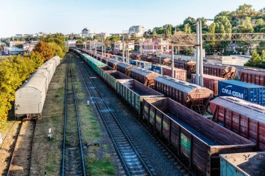 İçinde Cmaecm harfleri olan tren vagonları olan bir tersane. Tren vagonları birikti ve çok kalabalıklar. Tren istasyonu bir şehre yakındır.