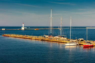 Sonunda bir sürü teknenin demirlediği büyük bir iskele. Su sakin ve gökyüzü berrak.