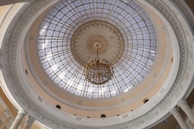 Büyük, süslü bir avize büyük beyaz bir kubbenin tavanında asılı. Avize, parlak bir cam kubbeyle çevrili. Işığın içeri girmesini ve odayı aydınlatmasını sağlıyor.