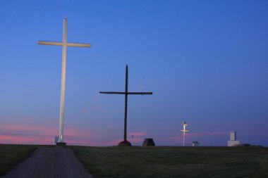 Akşam gökyüzünde bir haç parlıyor. Gökyüzü mavi ve güneş batıyor.