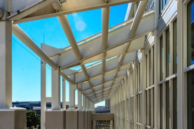 Beyaz çatılı ve arkasında mavi gökyüzü olan büyük beyaz bir bina. Binanın bir sürü penceresi ve geniş bir açık alanı var.