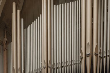 Bir sıra uzun, ince, beyaz borular, muhtemelen bir boru organı parçası. Borular, izleyiciye daha yakın görünen bazı borularla birlikte derinlik ve boyut duygusu yaratacak şekilde düzenlenmiş.