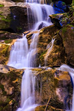 İçinde bir sürü su ve kaya olan bir şelale. Su kayalardan akıyor ve kayalar kahverengi.