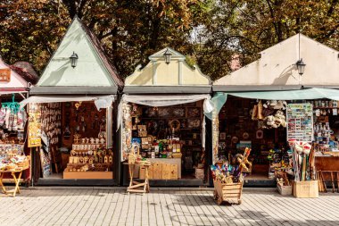 Tenteli ve tenteli üç küçük dükkan tuğla kaldırıma dizilmiş. Dükkanlar çeşitli ürünler satıyor, birkaç oyuncak ayı da dahil. Manzara canlı bir pazar ya da sokak fuarı gibi.