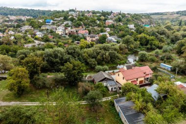 Küçük bir kasaba ve nehir olan bir kırsal bölge. Evler küçük ve ağaçlar yeşil.