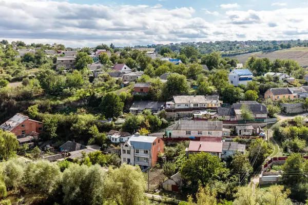 Evleri ve ağaçları olan küçük bir kasaba. Evler çoğunlukla kırmızı ve kahverengidir. Gökyüzü bulutlu.