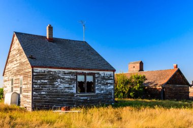 Baca ile küçük, eski bir ev bir tarlada oturur. Ev çimenler ve ağaçlarla çevrili.