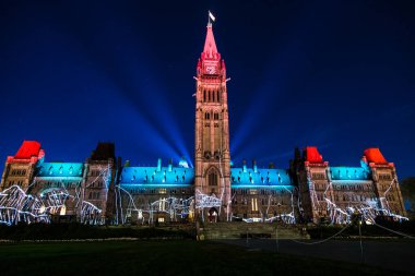 A large, red and blue building with a clock tower is lit up at night. The building is a government building, and the lights are shining brightly on it, creating a festive and celebratory atmosphere clipart