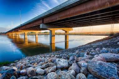 Bir köprü kayalık bir kıyı şeridine sahip bir nehri kapsar. Köprü beton ve çelikten yapılmıştır.