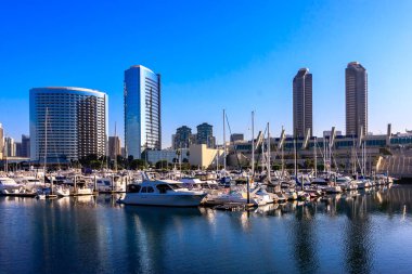 Suya yanaşmış bir sürü teknesi olan büyük bir marina. Su sakin ve gökyüzü berrak.