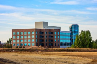 Cam kubbeli büyük bir bina kuru çim tarlasında duruyor. Bina ağaçlarla çevrili ve o bir otel. Gökyüzü açık ve güneş parlıyor. Huzurlu bir hava yaratıyor.