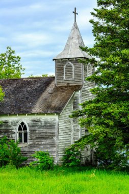 Çan kulesi ve üzerinde haç olan küçük, eski bir kilise. Kilise bir çimen tarlası ile çevrilidir.