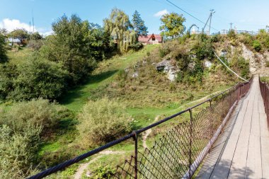 Uzakta evi olan bir tarlanın üzerinde köprü. Köprü ahşap ve metalden yapılmıştır.