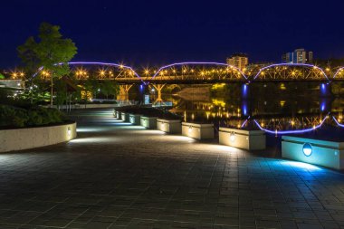 Geceleri bir köprü ışıldıyor. Işıklar suya yansıyor. Sahne huzurlu ve sakin, ışıklar rahatlatıcı bir atmosfer yaratıyor.