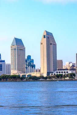 Ortasında büyük bir bina olan bir şehir silueti. Su sakin ve gökyüzü berrak.