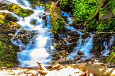 Kayalık bir yamaçtan akan bir su akıntısı. Su berrak ve kayalar pürüzsüz. Huzurlu ve huzurlu bir sahne.