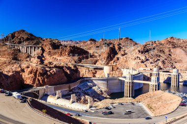 Bir dağın üzerine büyük bir baraj inşa edilir. Baraj büyük bir otoparkla çevrilidir. Park yerinde bir kaç kırmızı araba da dahil olmak üzere bir sürü araba var. Huzurlu ve huzurlu bir sahne.