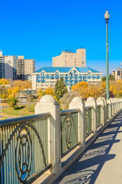 Üzerinde parmaklık olan bir köprü ve arka planda bir bina. Korkuluklar yeşil ve üzerinde bir tasarım var.