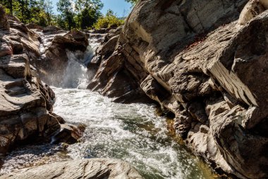 A river flows through a rocky canyon. The water is clear and the rocks are jagged. The scene is peaceful and serene clipart