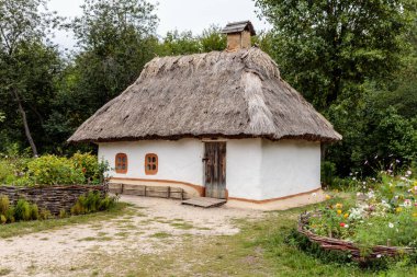 Bahçede sazdan çatısı olan küçük, eski moda bir ev var. Ev bir taş duvar ve bir çiçek bahçesi ile çevrilidir. Bahçe renkli çiçeklerle dolu, papatyalar, güller de dahil.