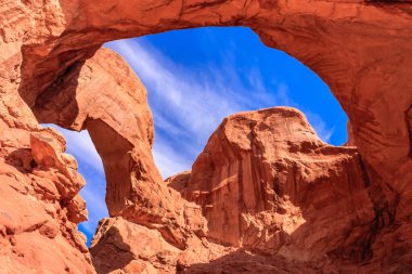 Üzerinde mavi bir gökyüzü olan bir kanyonda büyük bir kemer yolu. Kemer yolu taştan yapılmıştır ve kayalık bir manzarayla çevrilidir. Gökyüzü berrak ve parlak, bir açıklık ve özgürlük hissi yaratıyor.