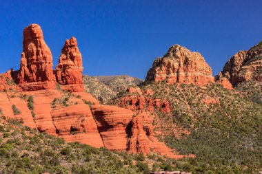 Kızıl kaya formasyonlu bir dağ sırası. Kayalar kırmızı ve gökyüzü mavi. Gökyüzünde hiç bulut yok.