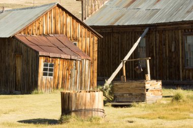 Önünde büyük ahşap bir yapı olan küçük, eski moda bir bina. Binanın ahşap kaplamalı ve teneke çatılı kırsal ve yıpranmış bir görünüşü var.