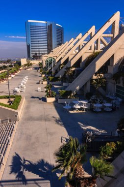 Dışarıda bir sürü masa ve sandalye olan büyük bir bina. Masalar beyaz, sandalyeler beyaz.