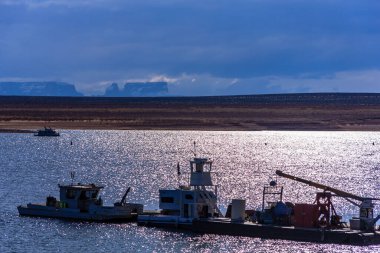 Başka bir teknenin yanına bir tekne yanaştı. Su sakin ve gökyüzü bulutlu.