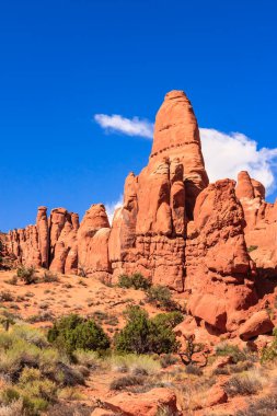 Ortasında büyük bir kaya olan bir dağ sırası. Gökyüzü mavi ve güneş parlıyor.